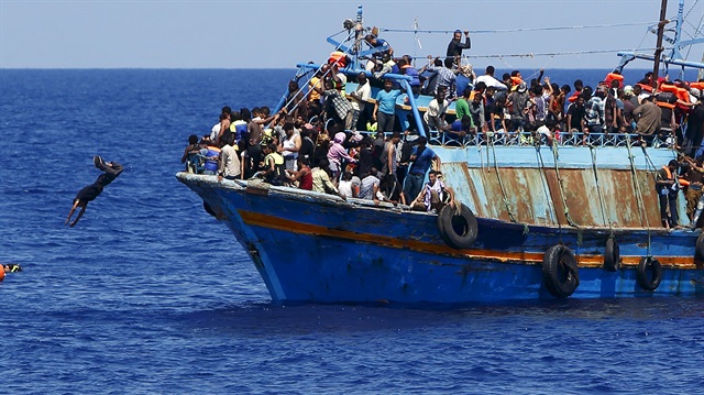 A migrant dives into the water from an overloaded wooden boat during a rescue operation 