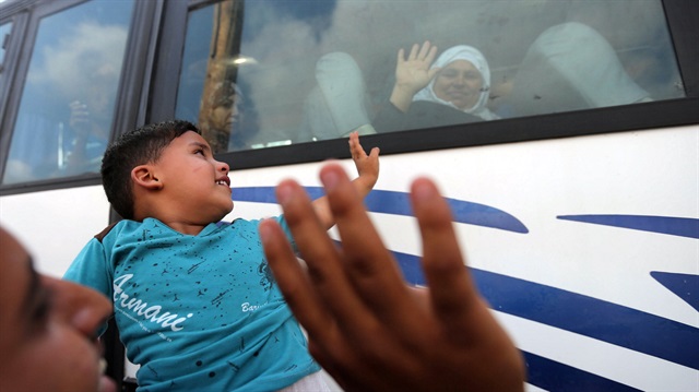 A Palestinian boy waves to his grandmother as she sits in a bus before she leaves for the annual  Haj