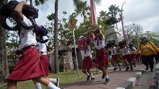 Students protect their heads as they run to a safe place during tsunami drill at Tanjung Benoa 