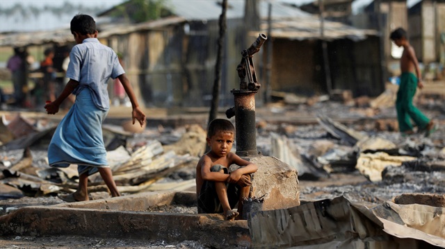 A boy sit in a burnt area after fire destroyed shelters at a camp
