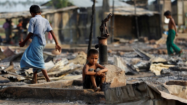 A boy sit in a burnt area after fire destroyed shelters at a camp