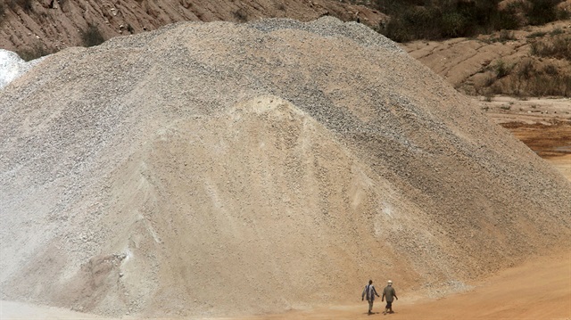 Workers walk past a pile of limestone at the Dangote Cement mine in Obajana village in Nigeria's central state of Kogi November 8, 2010.