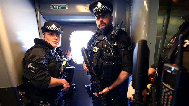 Armed police officers stand in a train.