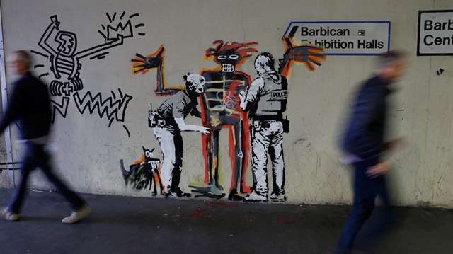 People walk past a mural painted by the artist Banksy near the Barbican Centre in London, Britain. 