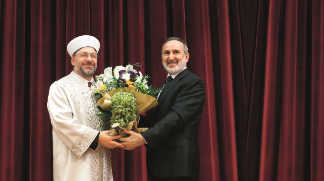 Ekrem Keleş cübbesini çıkartıp yeni başkan Ali Erbaş'a giydirdi ve ardından kendisine çiçek takdim etti.
