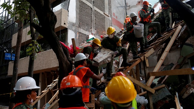 Mexican soldiers and rescue workers search for survivors in a collapsed building 