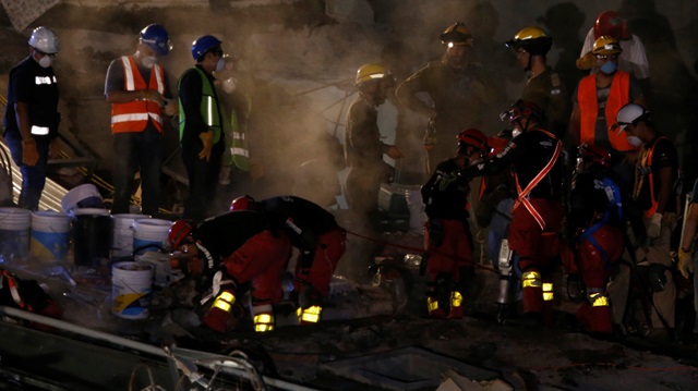 Members of rescue teams search for survivors in the rubble of a collapsed building