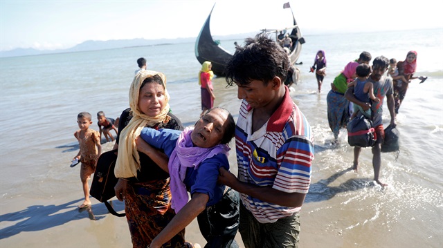 Rohingya refugees are assisted to get of a wooden boat that brought them from Myanmar