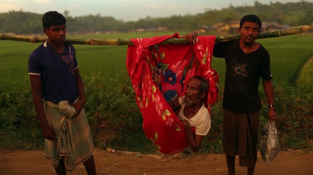 Arakanlı iki genç, hasta olan babalarını omuzlarında taşıyarak Bangladeş'e getirdi.