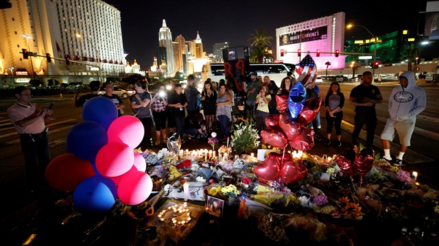 People gather at a makeshift memorial in the middle of Las Vegas Boulevard