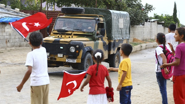 Çocuklar, ellerinde Türk bayraklarıyla askerleri karşılıyor.