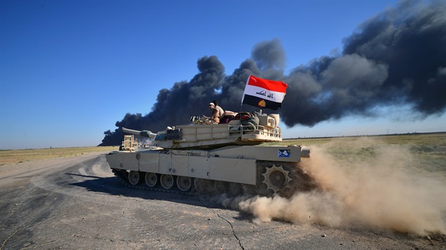 Iraqi army members ride on a tank on the outskirts of Hawija, Iraq.