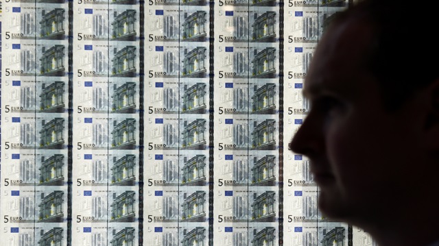 A man is seen in front of a sheet of 5 euro notes 