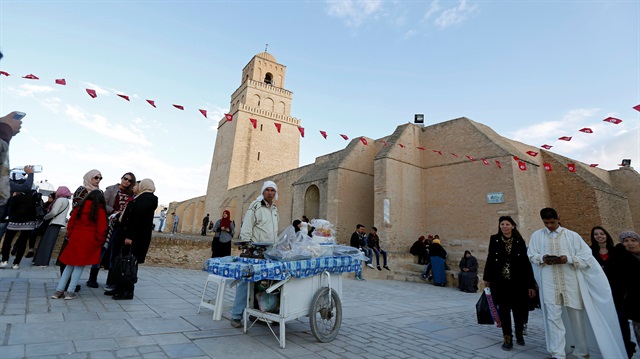 People pass a street vendor selling traditional confectioneries in front of the Uqba ibn Nafi 