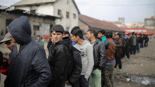 Migrants stand in line to receive free food 