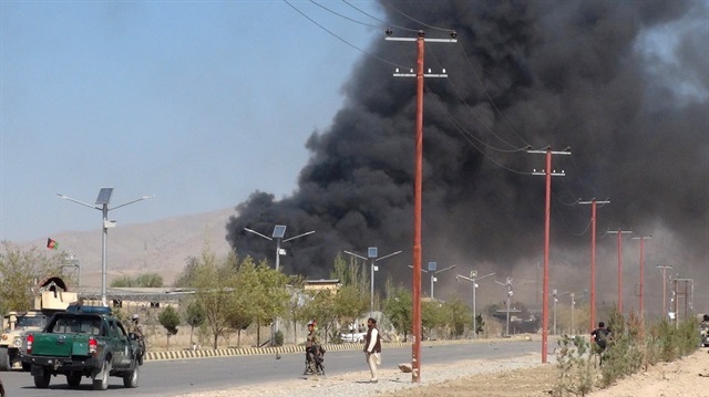 Smoke rises from police headquarters while Afghan security forces keep watch 