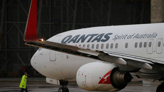 A ground staff member prepares to detach his communication cord from a Qantas Boeing 737