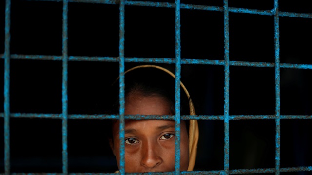 A Rohingya refugee who crossed the border from Myanmar this week stands at a window 