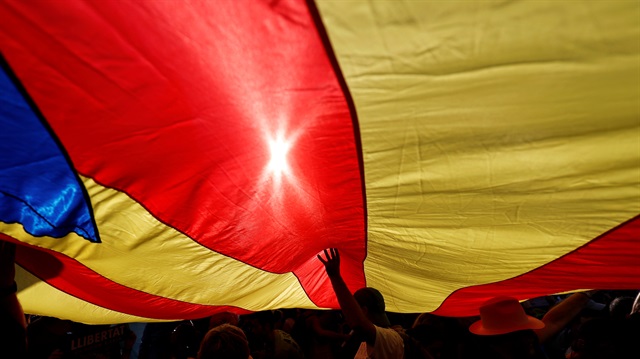People stand under a giant separatist Catalonian flag during a demonstration