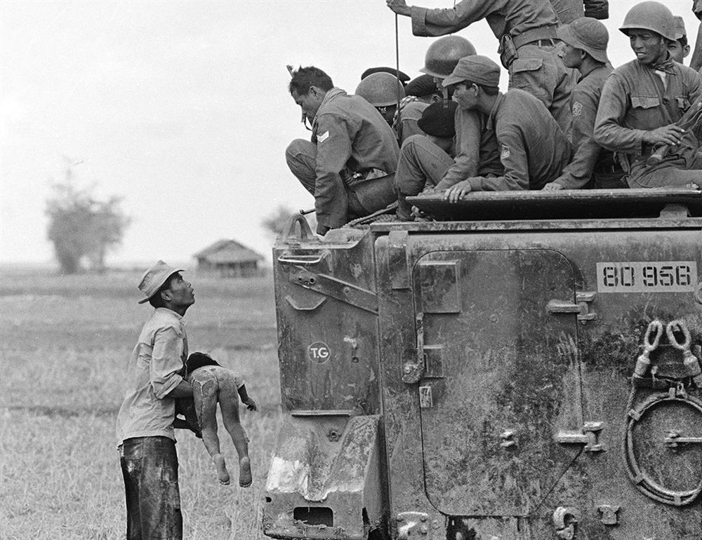 19 Mart 1964'te Güney Vietnam Ordusu'na ait bir zırhlı aracın yanına gelerek Kamboçya sınırına yakın bir köyde öldürülen bebeğinin cansız bedenini gösteren bir baba. 