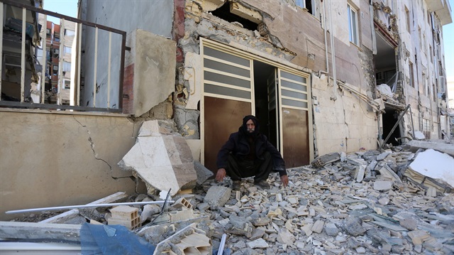 A man sits outside a damaged belonging following an earthquake in Sarpol-e Zahab county in Kermanshah, Iran.