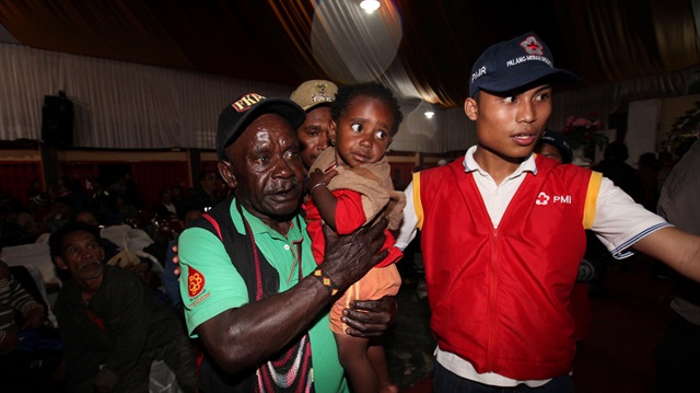 A member of the Indonesian Red Cross assists evacuees from villages in Timika, Mimika, Papua province