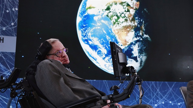 Physicist Stephen Hawking sits on stage 