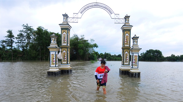 A woman walks through a flooded area after a cyclone hit the area at Tlingsing village