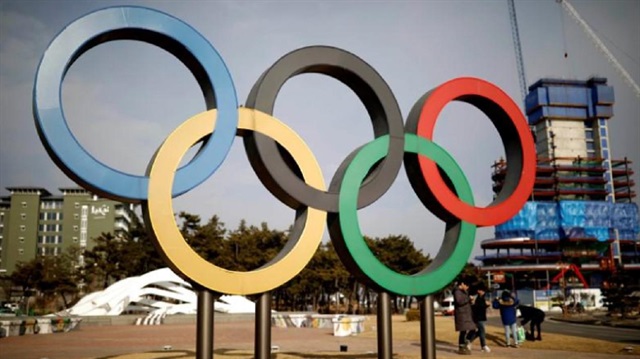 People walk past the Olympic rings in Gangneung, South Korea 
