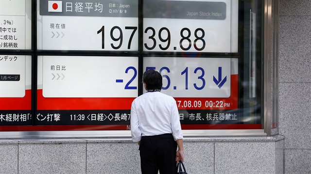 A man looks at an electronic board showing Japan's Nikkei average outside a brokerage