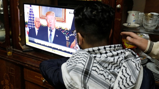 A Palestinian refugee watches a televised broadcast of U.S. President Donald Trump 