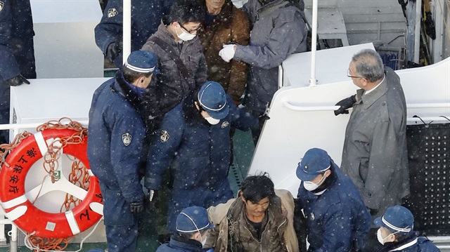 Japanese policemen escort the crew of a North Korean boat at a port in Hakodate