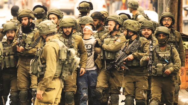 22 İsrail askerinin ortasında gözleri bağlı bir şekilde gözaltına alınan 16 yaşındaki Filistinli gencin fotoğrafı, İsrail’in Filistinlilerden ne kadar korktuğunu da tüm dünyaya gösterdi.
