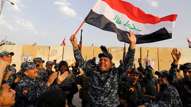 A member of Iraqi Federal Police waves an Iraqi flag as they celebrate victory