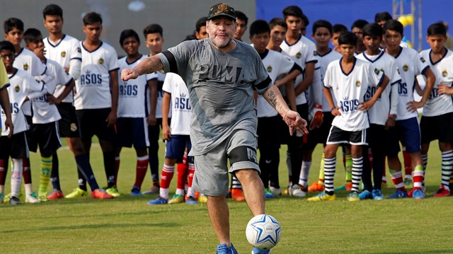 Argentina's soccer legend Diego Maradona kicks a ball as he attends a workshop with school students in Kadambagachi village
