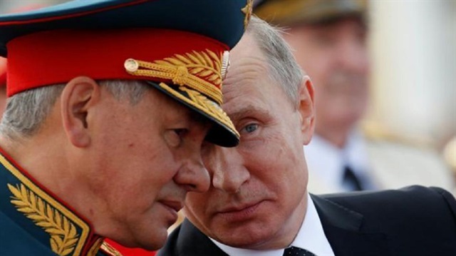 Russian President Vladimir Putin speaks with Defence Minister Sergei Shoigu as they attend the Navy Day parade in St. Petersburg, Russia, 