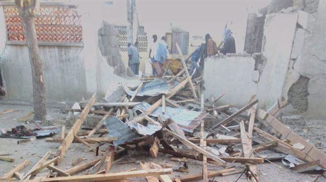 People stand near the damage following an attack on a mosque in the town of Gamboru