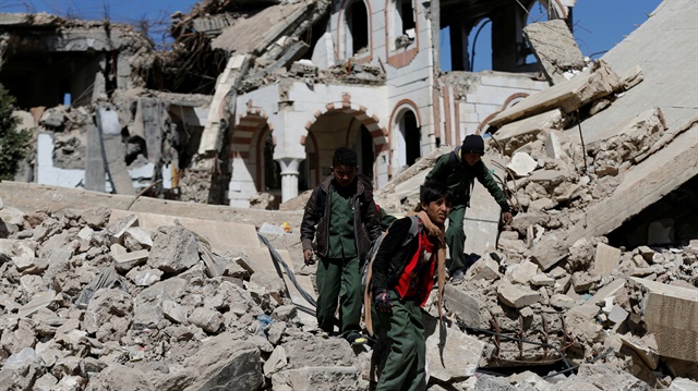File Photo: Boys walk on the wreckage of a building hit by air strikes two years ago in Sanaa