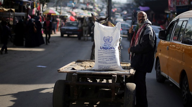 A Palestinian man stands next to a cart carrying a flour sack distributed by the United Nations 
