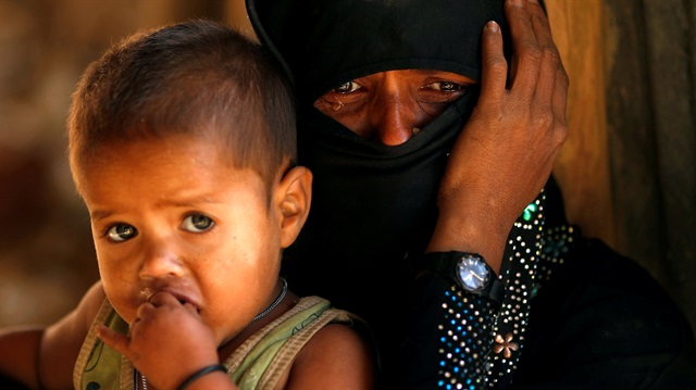 Rohingya refugee cries next to her son, outside a temporary mosque at Kutupalong
