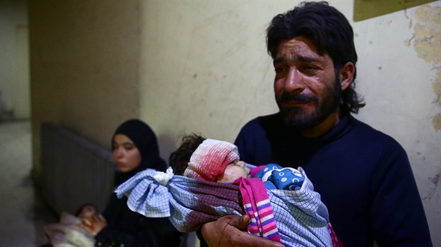 Şam'ın Doğu bölgesinde hava saldırısında katledilen 2 yaşındaki oğlunun minik bedenini tutan baba Mahmoud al-Bash... (Fotoğraf: Reuters)