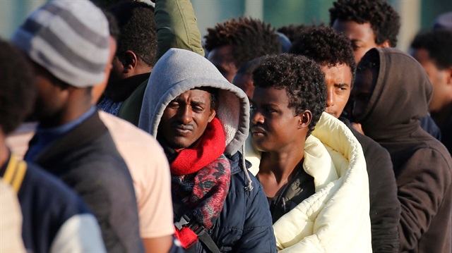 Migrants from Ethiopia and Eritrea queue in line during a food distribution 