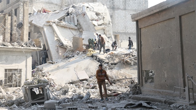 Syrians walk over wreckages of collapsed buildings after war crafts belonging to Assad Regime carried out airstrikes in the de-escalation zone of Hamouriyah, in besieged Eastern Ghouta in Damascus, Syria 