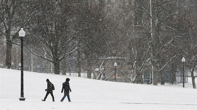 Pedestrians walk through Boston Common during a winter snow storm in Boston