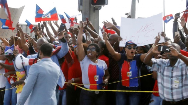 Demonstrators hold up Haitian flags and shout as the motorcade of U.S. President Donald Trump passes in West Palm Beach, Florida, U.S., January 15, 2018. REUTERS/Kevin Lamarque