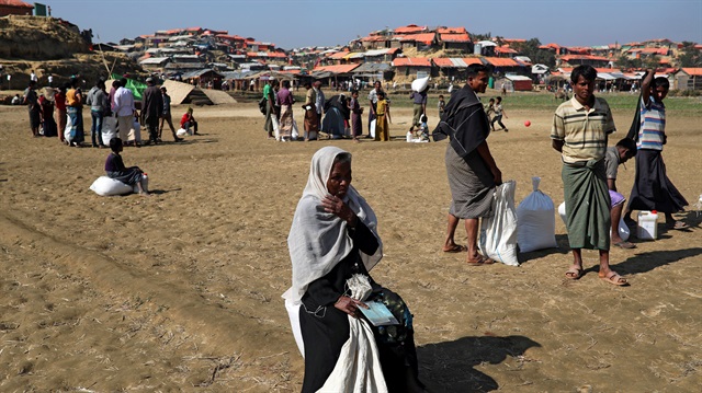 Rohingya refugees sit on the ground after collecting aid supplies in Thyingkhali 