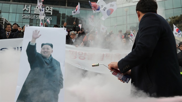 A member of a South Korean conservative civic group attempts to burn a banner depicting North Korean leader Kim Jong Un during a protest opposing North Korea's participation in the 2018 Pyeongchang Winter Olympics, in Seoul, South Korea, January 22, 2018. Yonhap via REUTERS 