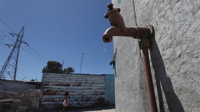 Residents walk past a leaking communal tap in Khayelitsha township, near Cape Town, South Africa, December 12, 2017. Picture taken December 12, 2017. REUTERS/Mike Hutchings