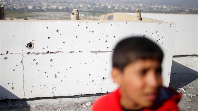 Palestinian boy stands on a residential building rooftop that was damaged in an Israeli air strike in the northern Gaza Strip