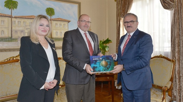 Karaloğlu, Letonya Büyükelçisi Pteris Krlis Elferts’e Antalya’nın su altındaki zenginliklerini anlatan “Su Altı Cenneti Antalya” kitabını hediye etti